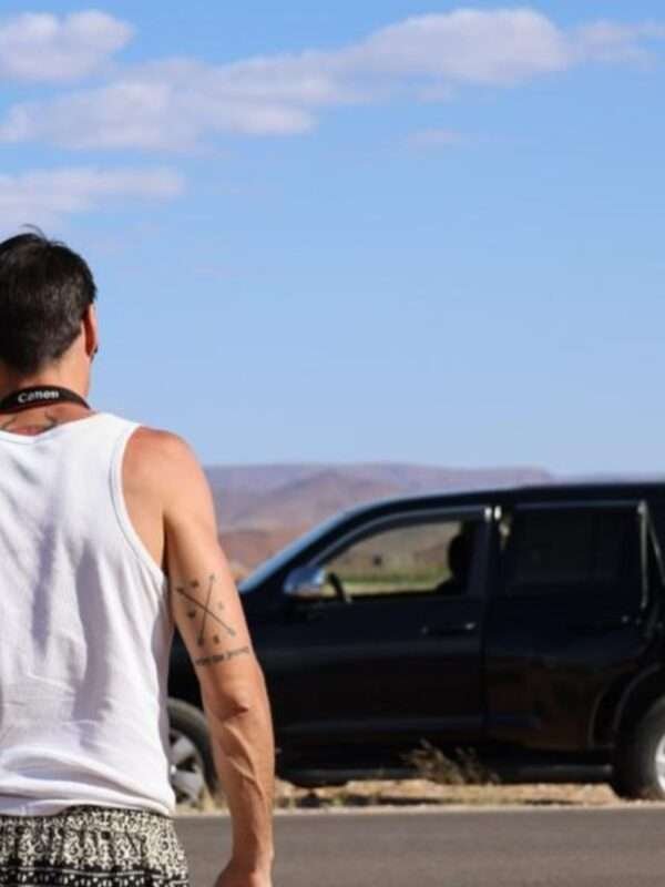 Image is for a tourist during our Moroccan holiday tour from Marrakech to Fes. The picture show the back of the man with a Toyota Prado in the background