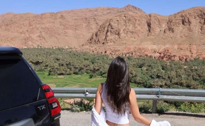 The image is for a tourist in Todra Gorge with SUV in the background