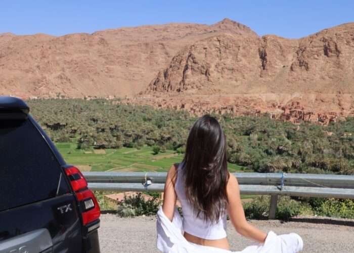 The image is for a tourist in Todra Gorge with SUV in the background